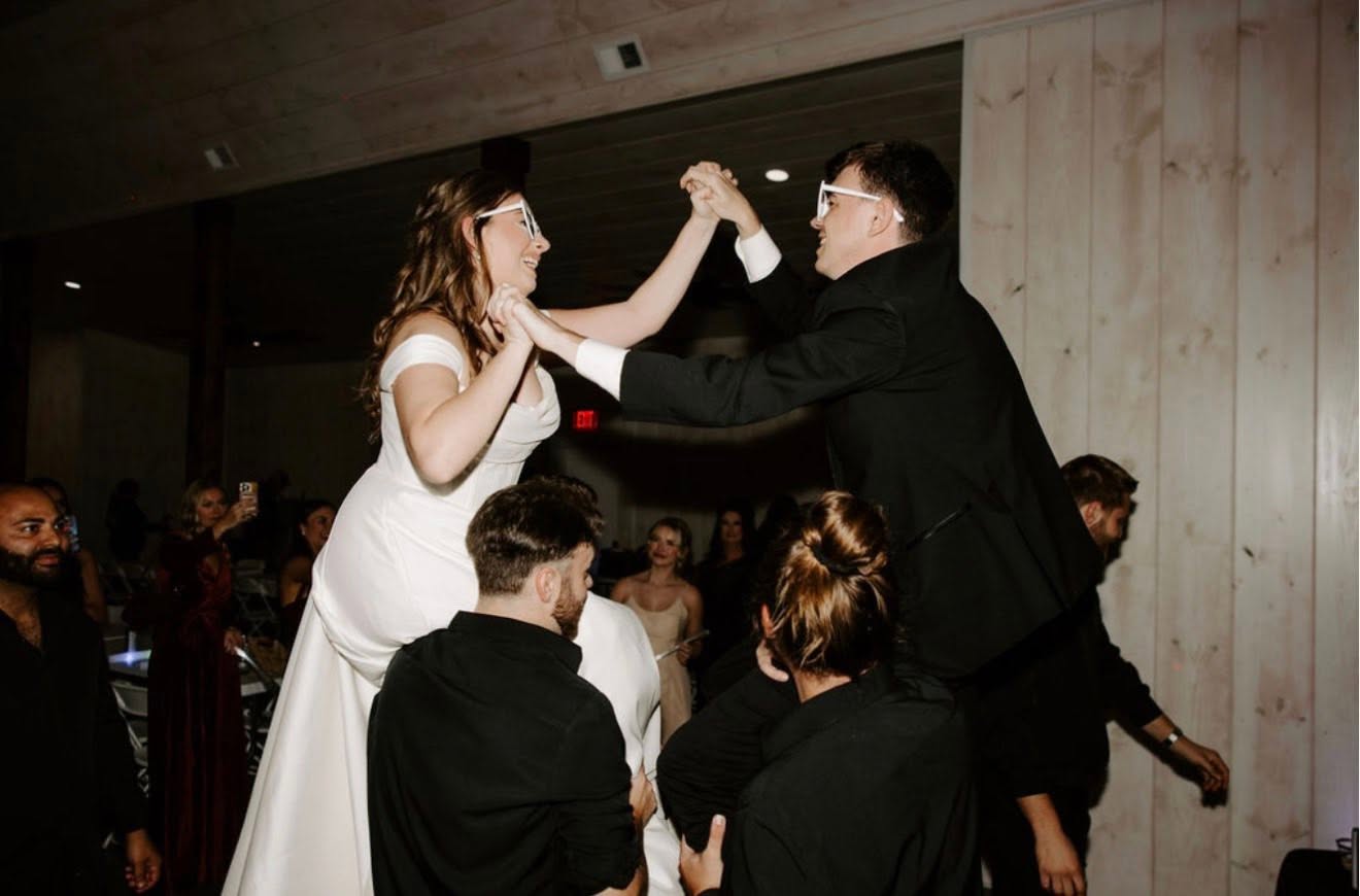 Newlyweds celebrating on the dance floor as guests cheer inside the reception hall