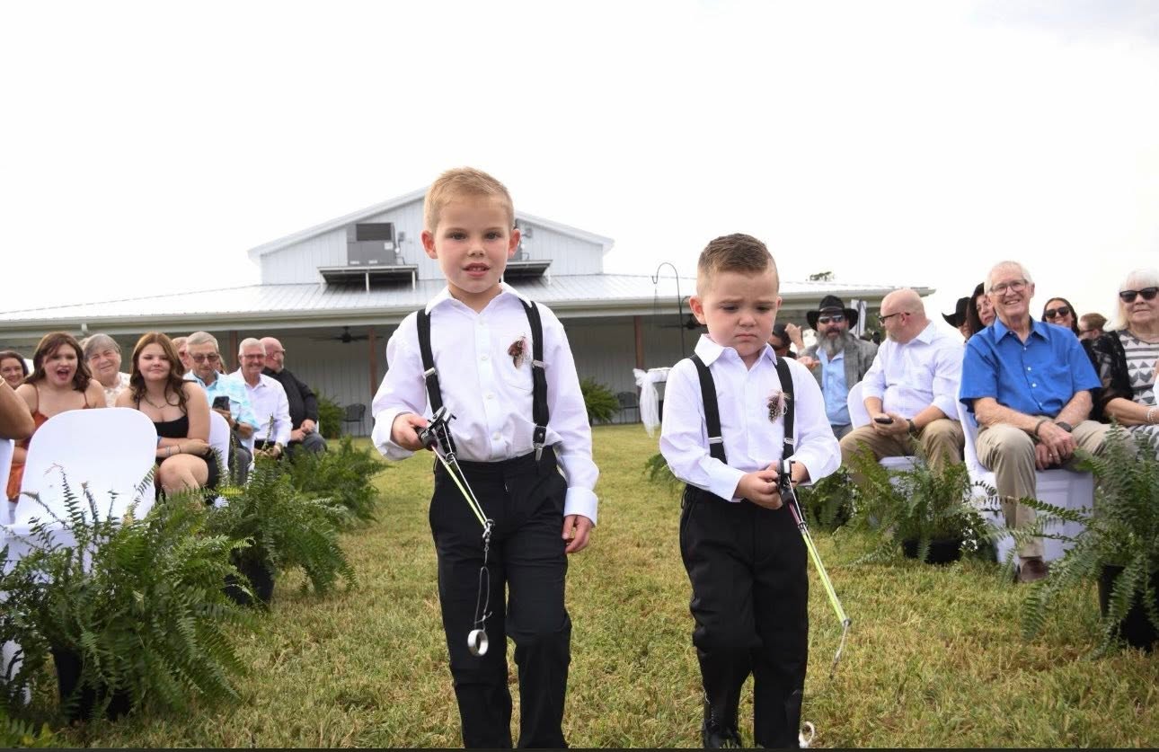 Two ring bearers walking down the aisle in front of guests seated for the ceremony