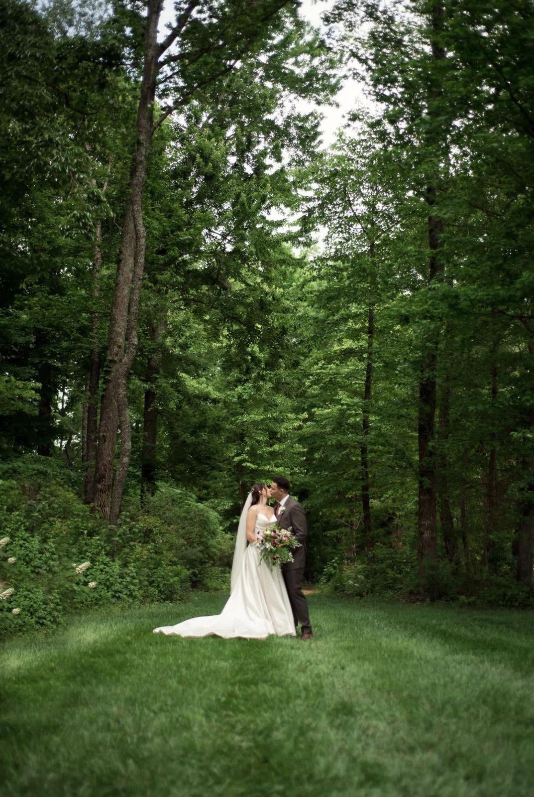 Bride and groom kissing in the lush green forest at Mirewood in spring